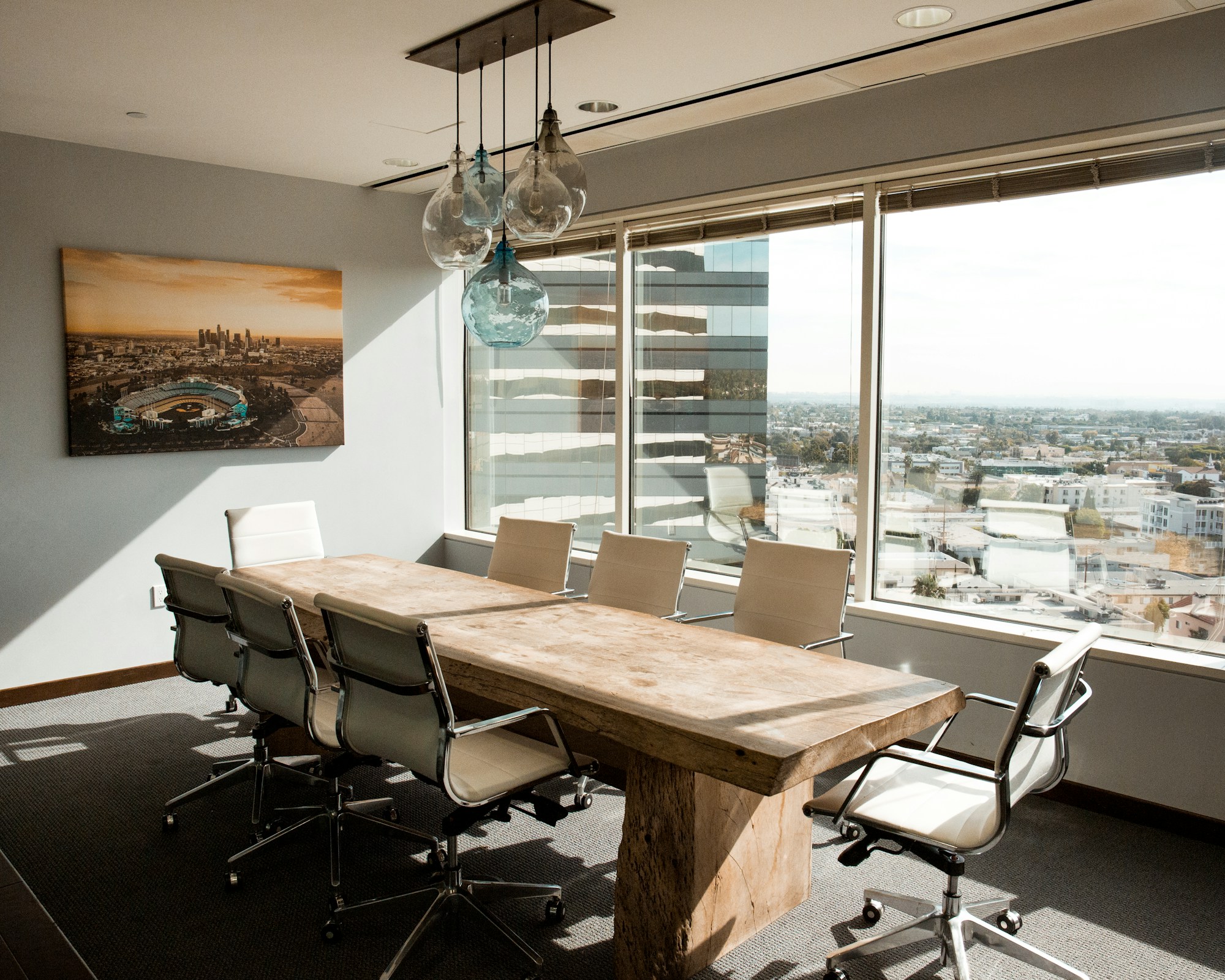 A daylit boardroom with a beige wooden conference table