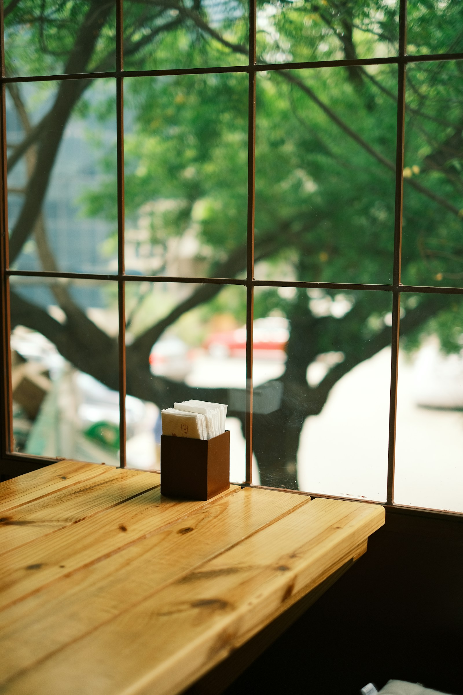 A wooden table next to a window in quiet daylight